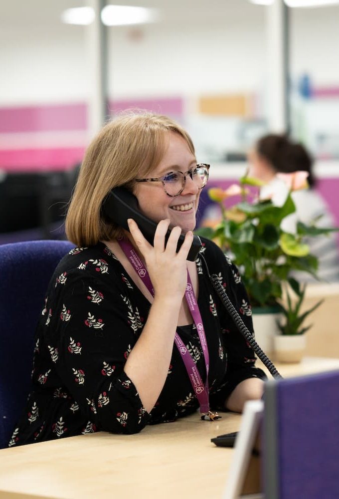 DSCF0719 (2) Woman in the Cansford Labs office talking on the phone with a smile on her face.